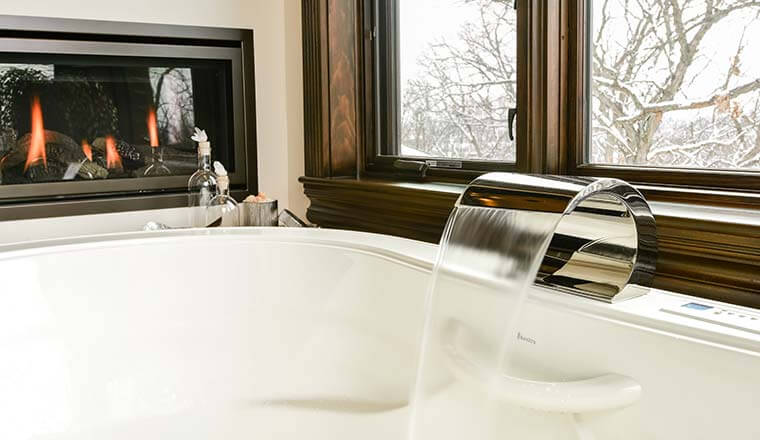 Tub faucet filler and nearby fireplace in an Urbandale, Iowa master bathroom remodel by Silent Rivers