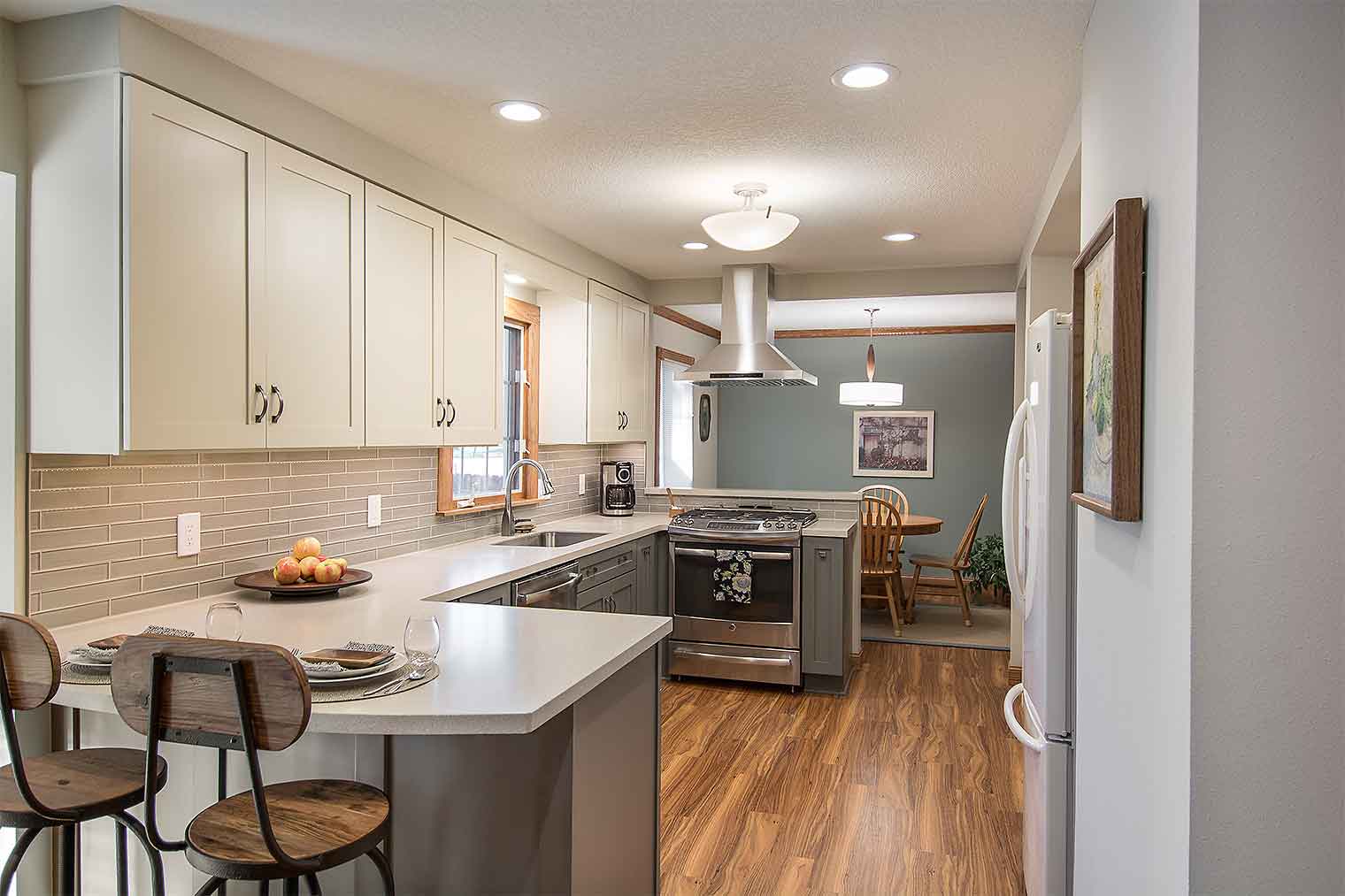 Kitchen with gray and cream cabinets, counter top eating area, dining area by Des Moines kitchen remodeler Silent Rivers