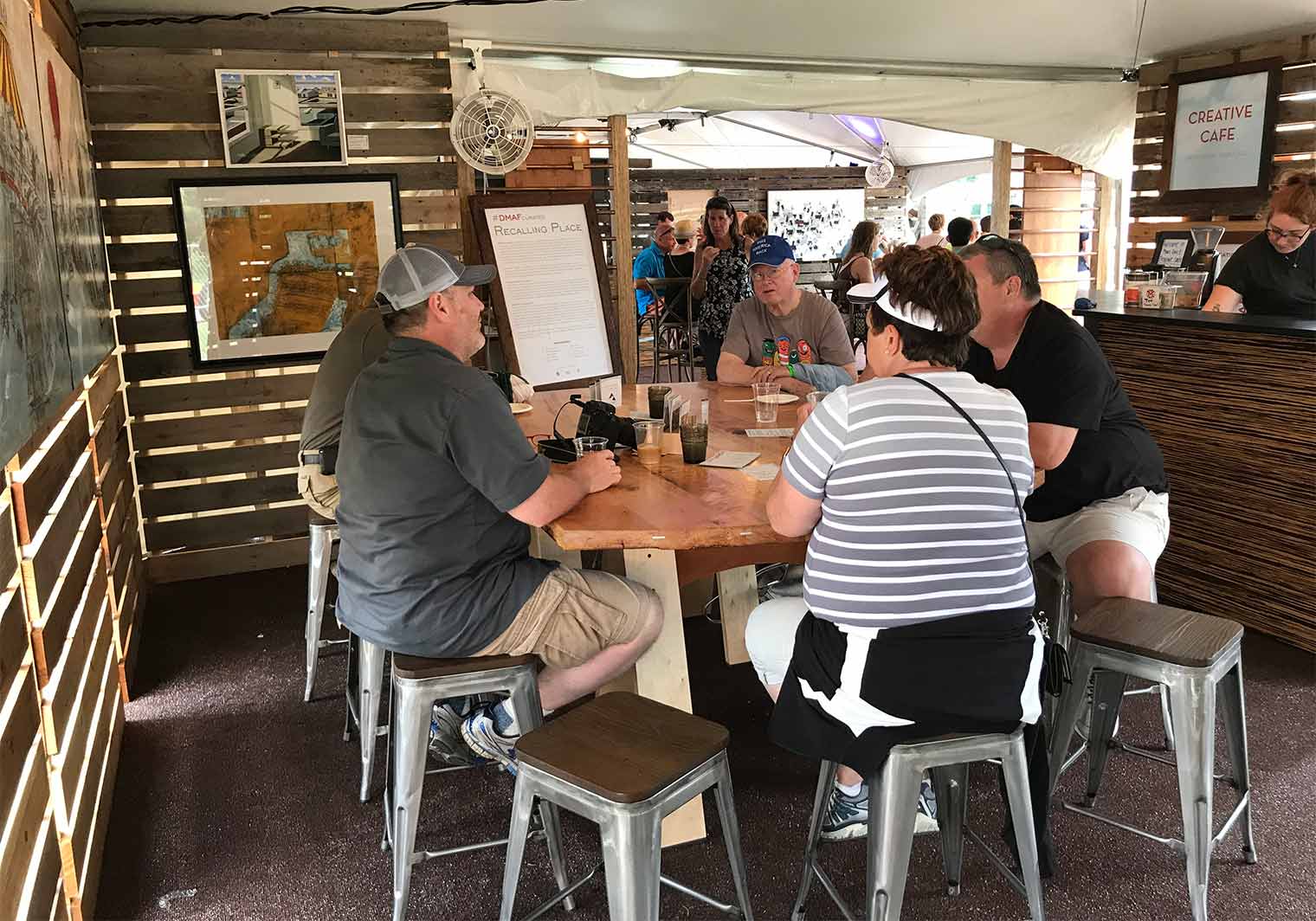 Chaden Halfhill talks with Des Moines Arts Festival Patrons around the Gathering Table in the Festival Salon inside the Silent Rivers VIP Club
