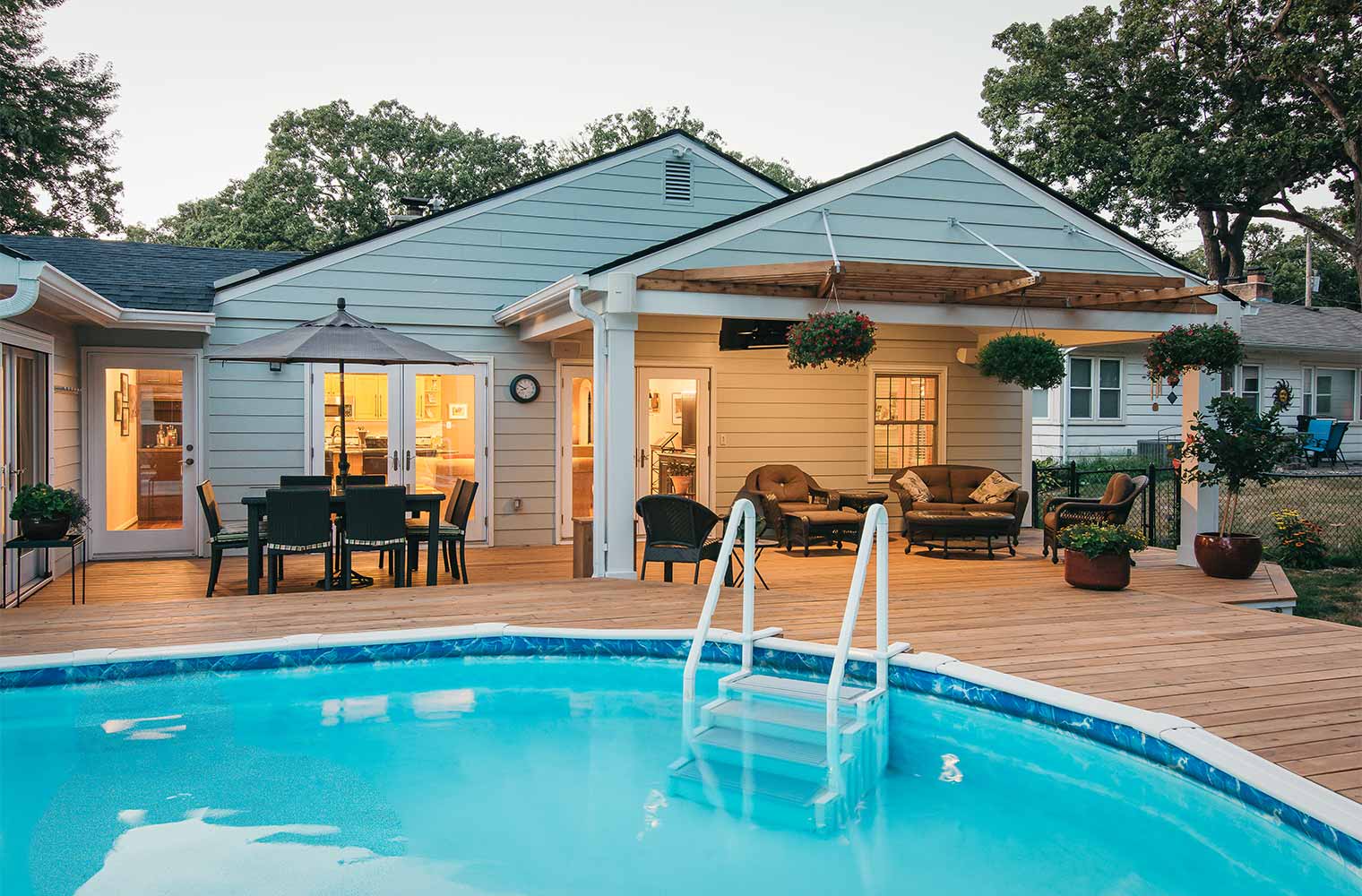 new roof over covered outdoor entertaining area by pool blends into style of midcentury ranch home in Des Moines by remodeler Silent Rivers