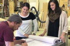 Caitlin Cuevas and Amie Schurman review architectural plans with woodshop artisan Alex Schlepphorst.
